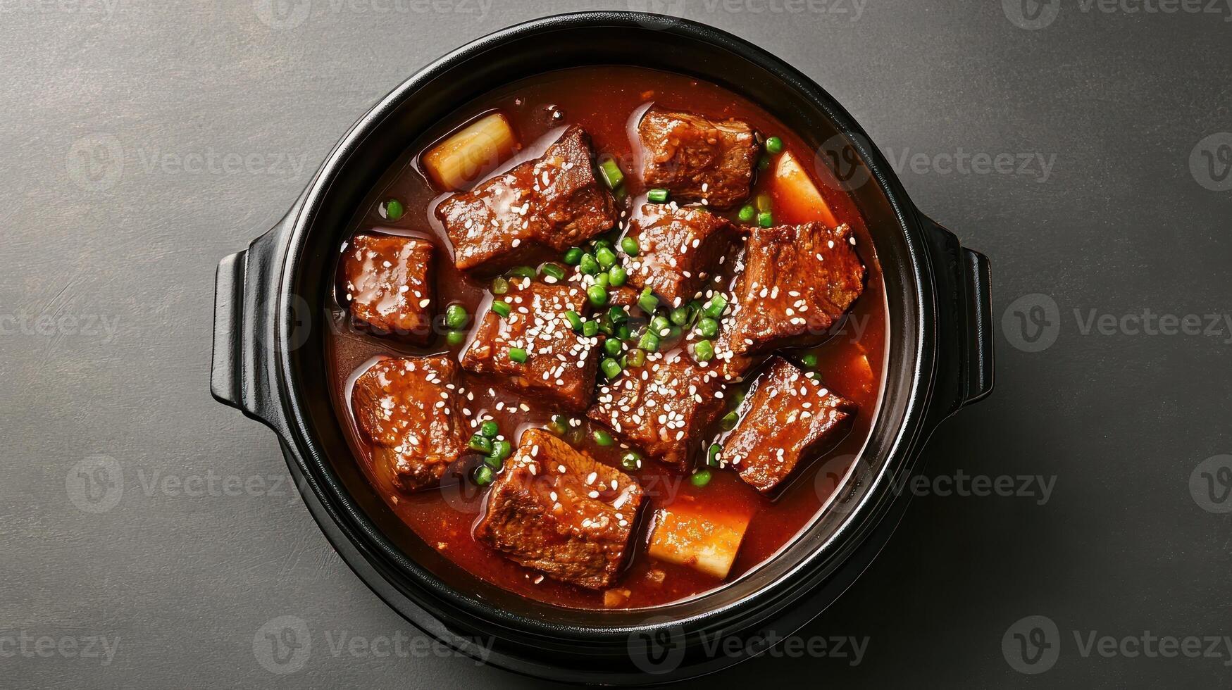 Braised beef chunks in pot served with sesame, peas and potato overhead shot. Possible use cookbook photo