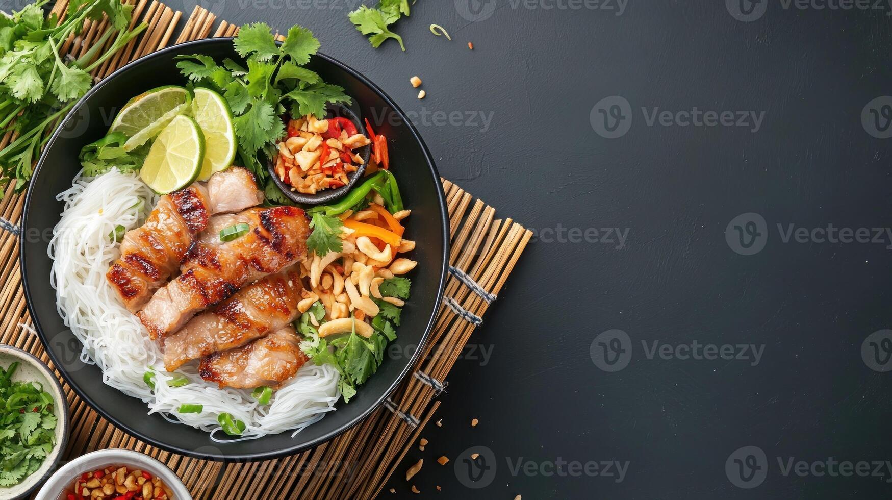 Delicious Vietnamese vermicelli noodle bowl, sliced beef, herbs, lime, chillies on bamboo mat photo