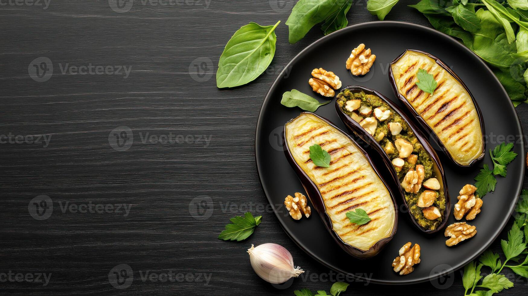Grilled eggplants on a dark plate with basil and walnuts. Delicious appetizer or side dish photo