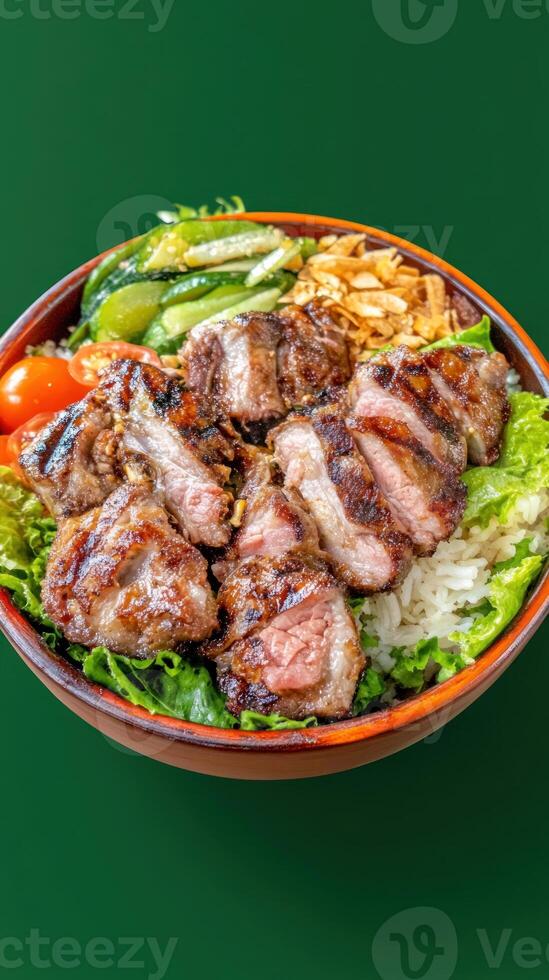 Grilled meat dish in bowl Food bowl with salad, rice, tomatoes and greens on green background photo