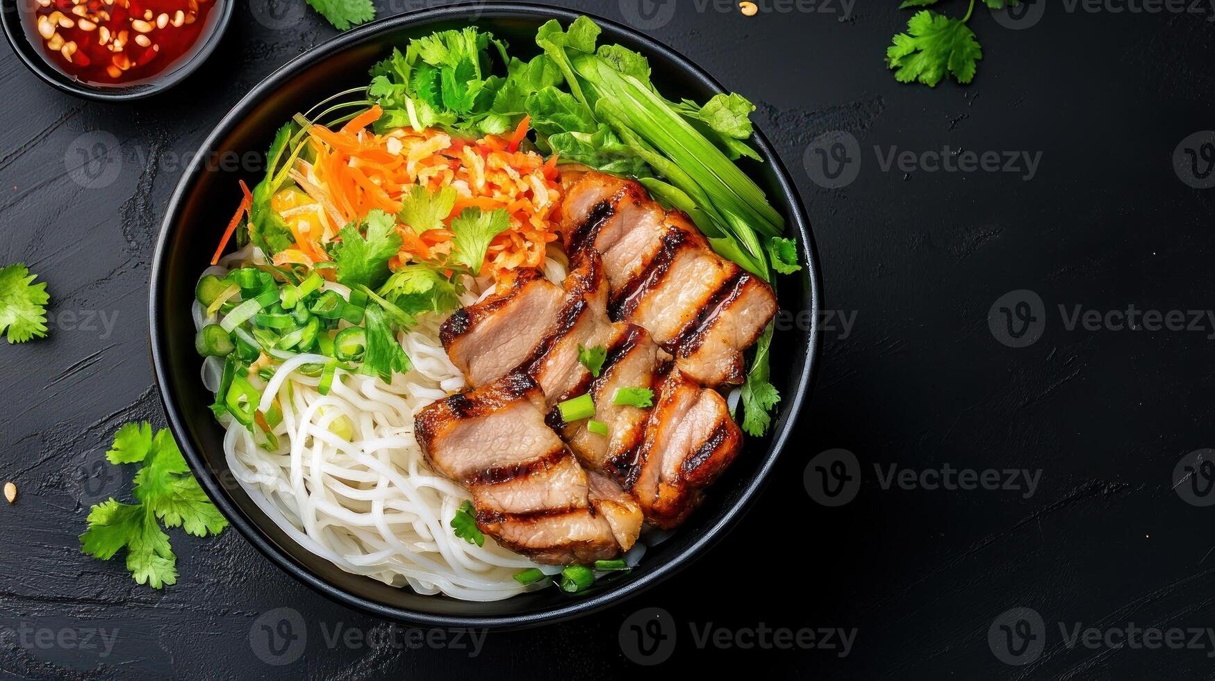 Grilled beef and rice noodles in a bowl with vegetables on a black background. Healthy eating photo