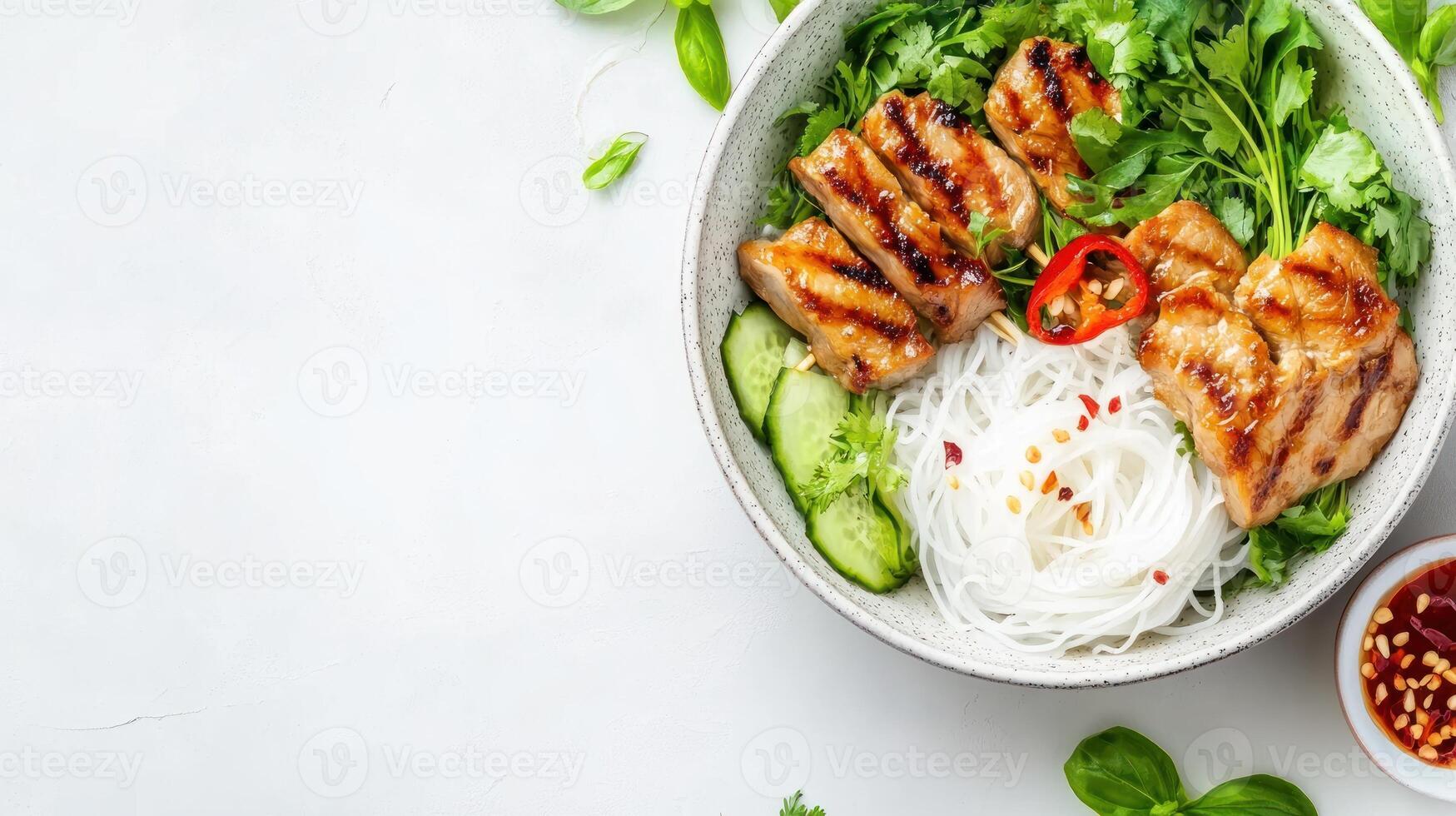 Grilled beef, noodles, and fresh herbs are served in a ceramic bowl as part of an Asian salad photo