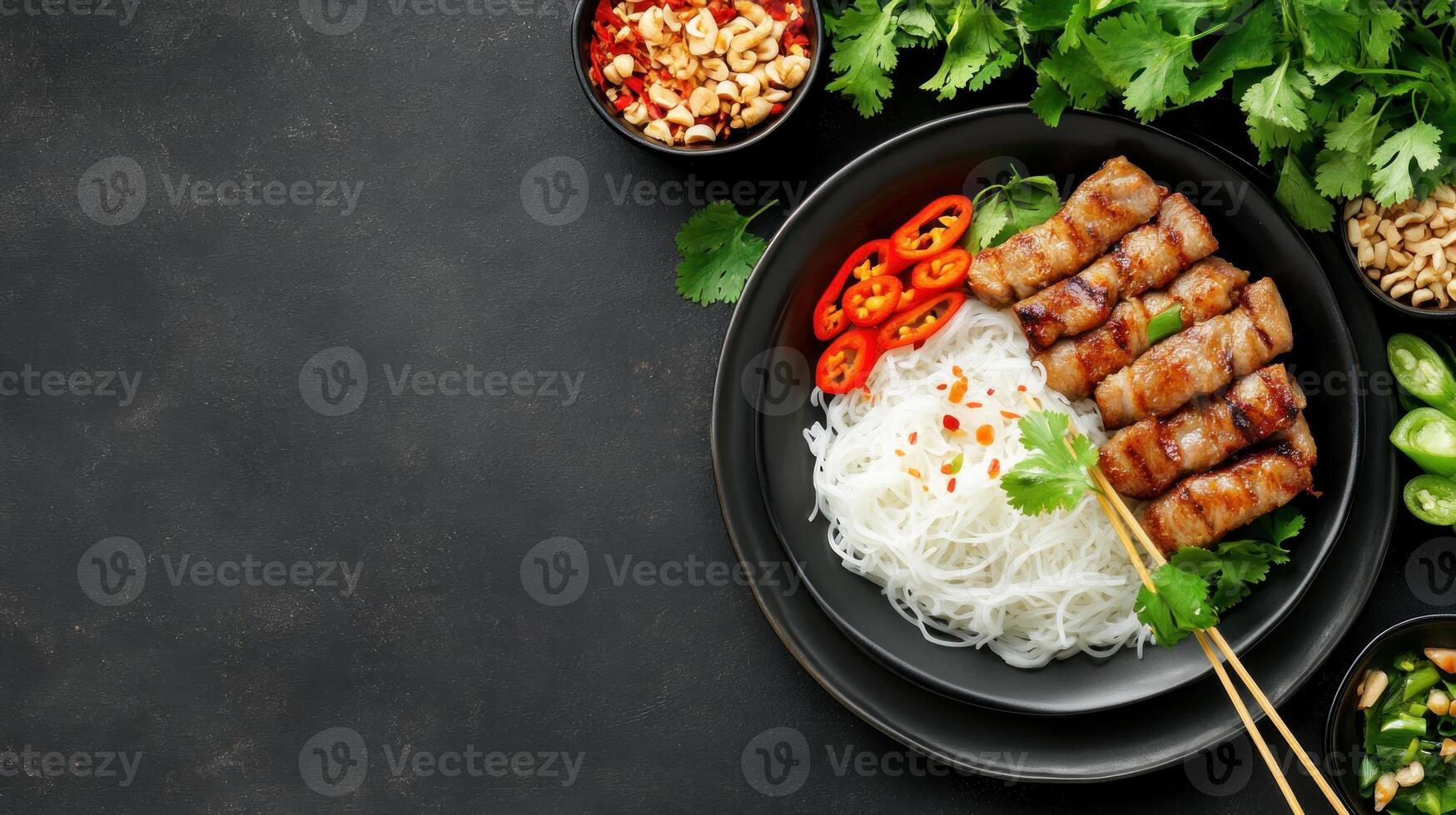 Grilled pork with rice noodles, fresh herbs chilli on black plate. Copy space for menu or recipe photo