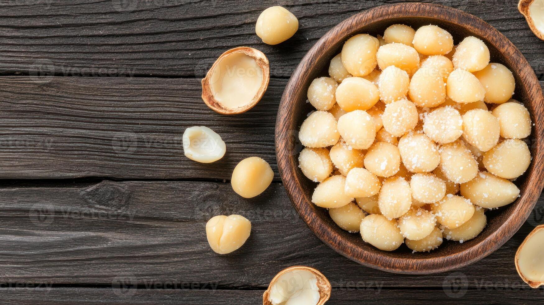 Macadamia nuts in bowl on dark wood table, ideal for healthy snacks, cooking or ingredients uses photo