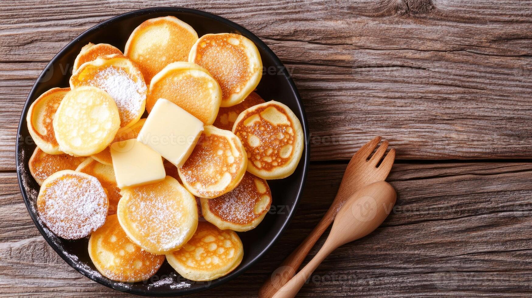 Mini pancakes with butter on a plate with cutlery and wooden background. Use for recipes, blogs photo