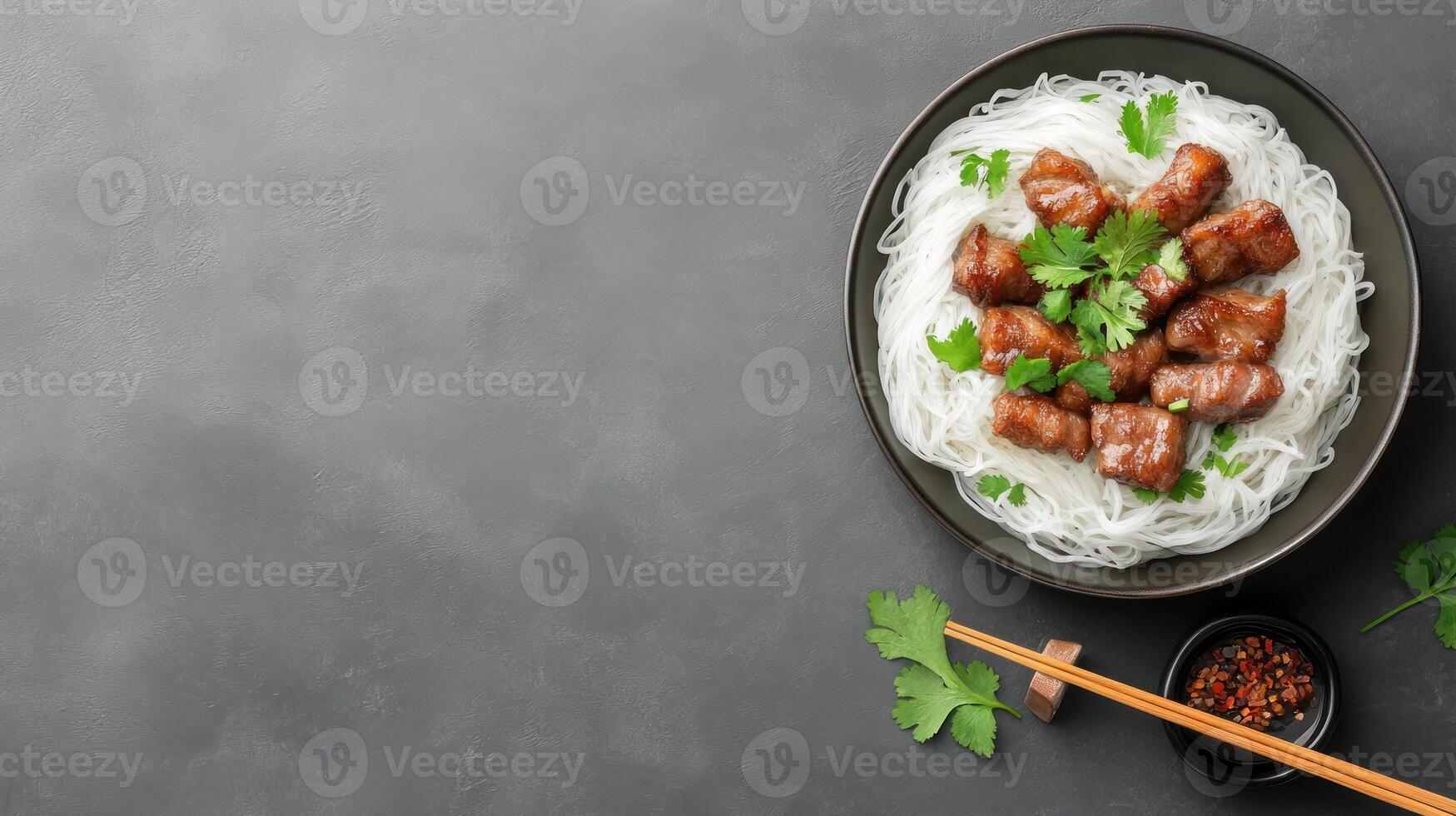Noodles with meat dish on a plate. Condiments and chopsticks alongside dish on grey background photo