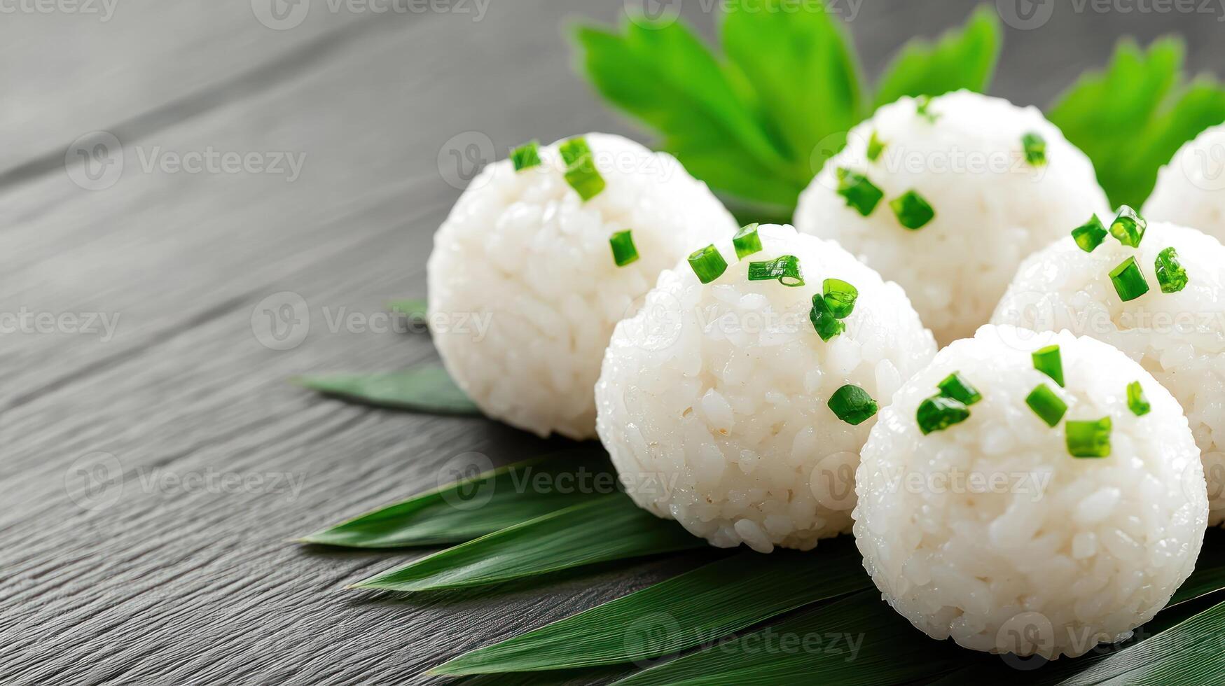 Rice balls with green garnish on leaves, resting on a gray wood surface. Food photography photo