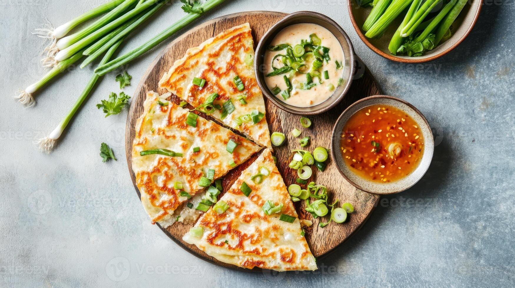 Scallion pancakes with dipping sauce on a round wooden board for snack or appetizers photo