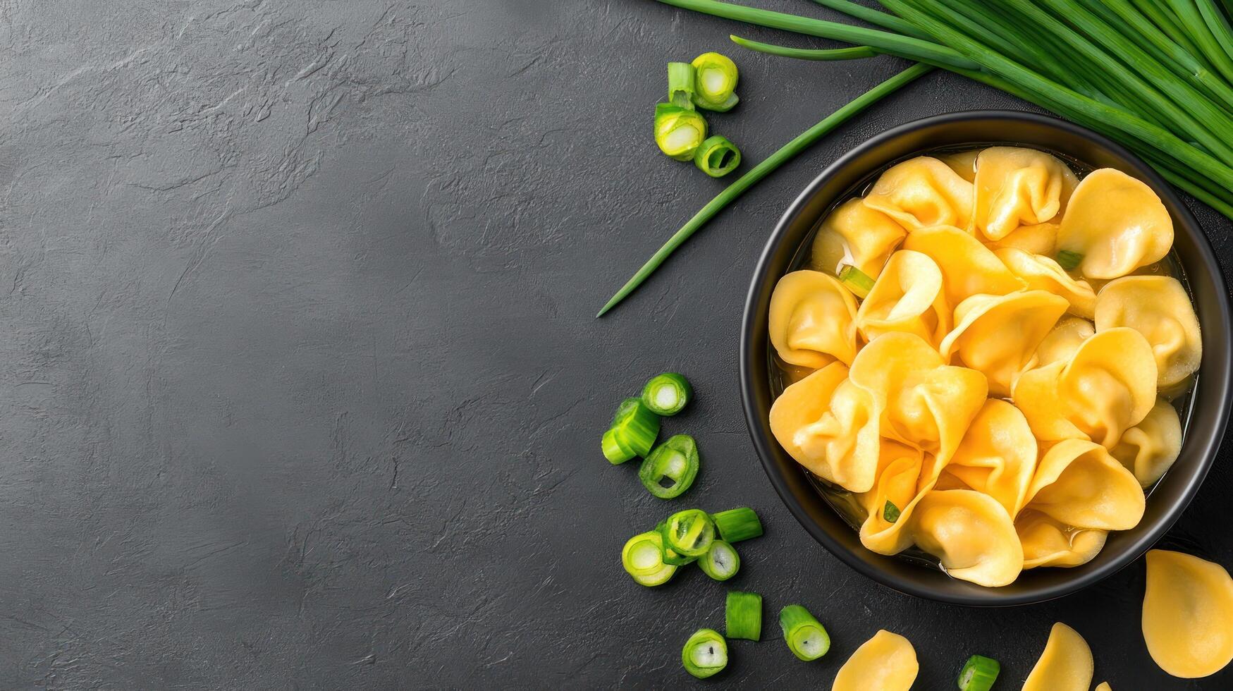 Tortellini soup with chives. Comfort food served in a bowl on black background photo