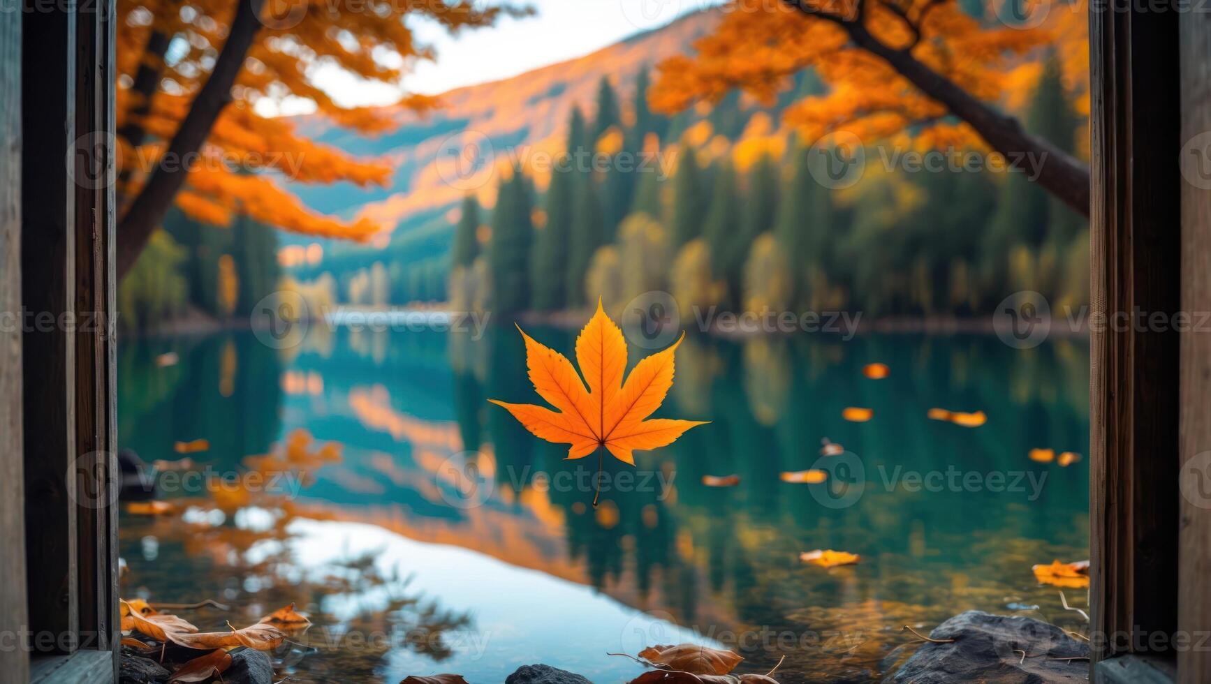 Orange Autumn Leaf Floating on Lake with Fall Foliage Backdrop photo