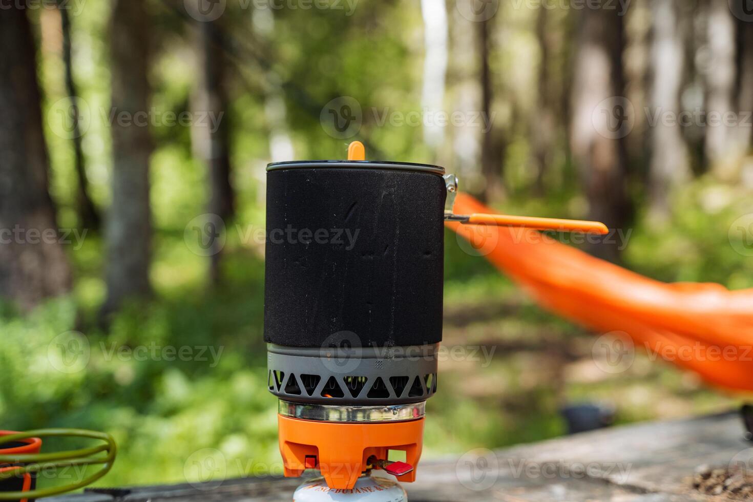 In the serene woods, there is a wooden table that supports a stove, creating a unique scene amidst the beauty of nature. It adds a touch of warmth and functionality to the environment photo