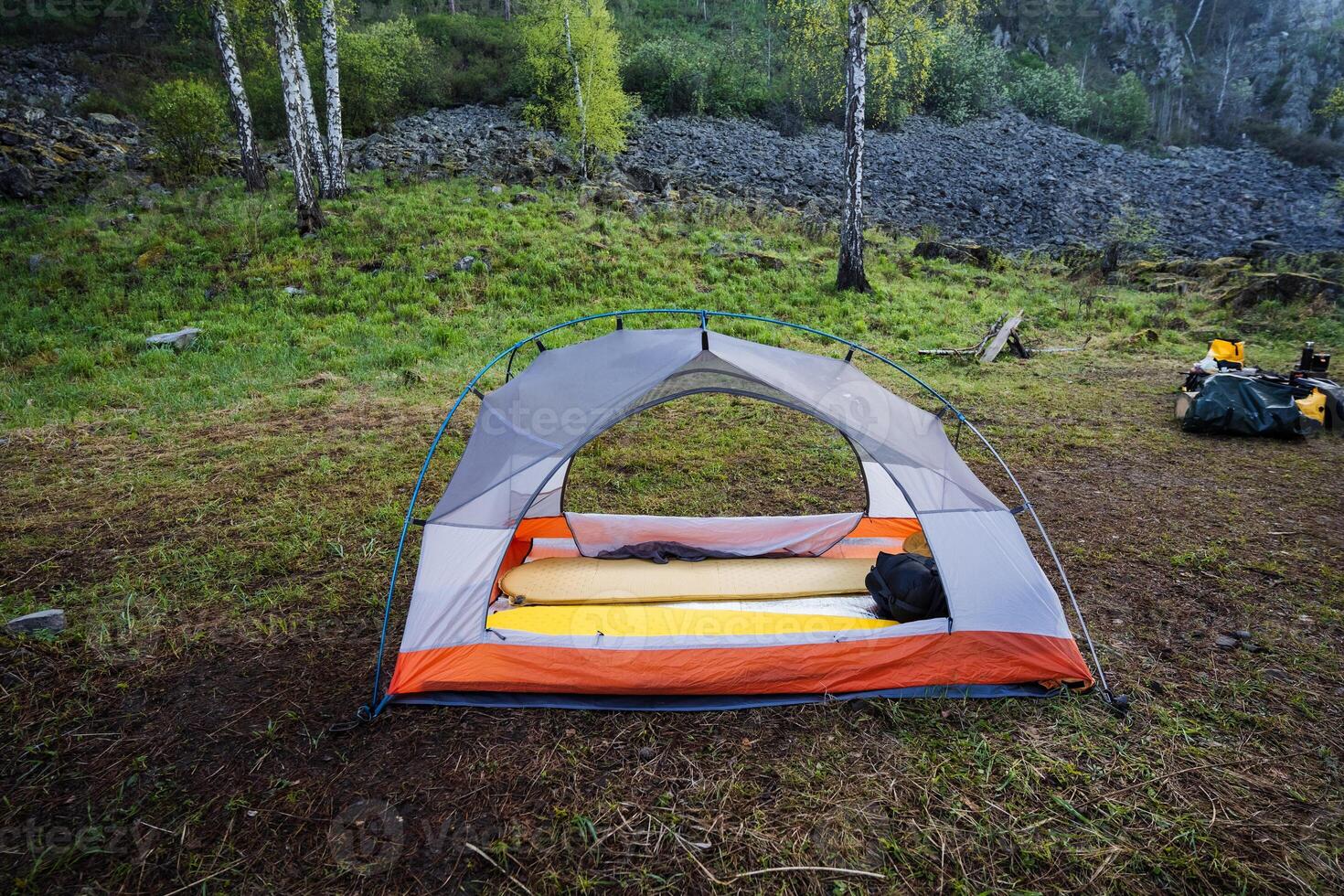 A serene camping scene beautifully showcases a cozy tent setup nestled within a lush green forest, embodying both adventure and tranquility, inviting everyone to explore the wonders of nature photo