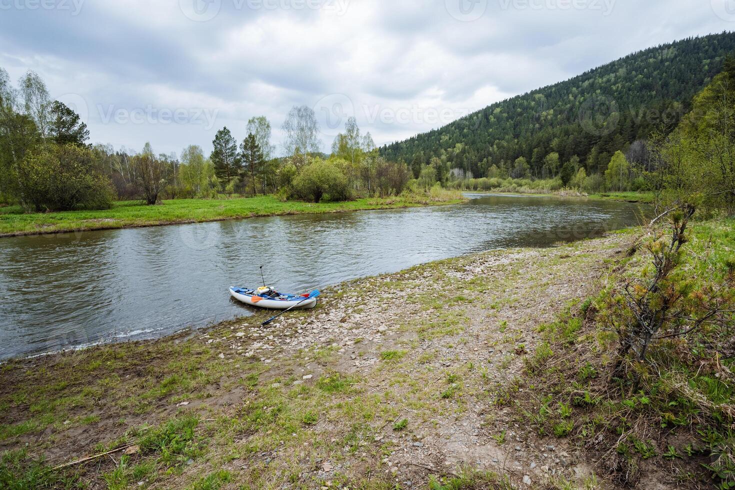 A charming little boat rests peacefully at a tranquil shoreline, perfectly framed by lush greenery and rolling hills that add to the feeling of serenity, inviting everyone to relax and contemplate photo