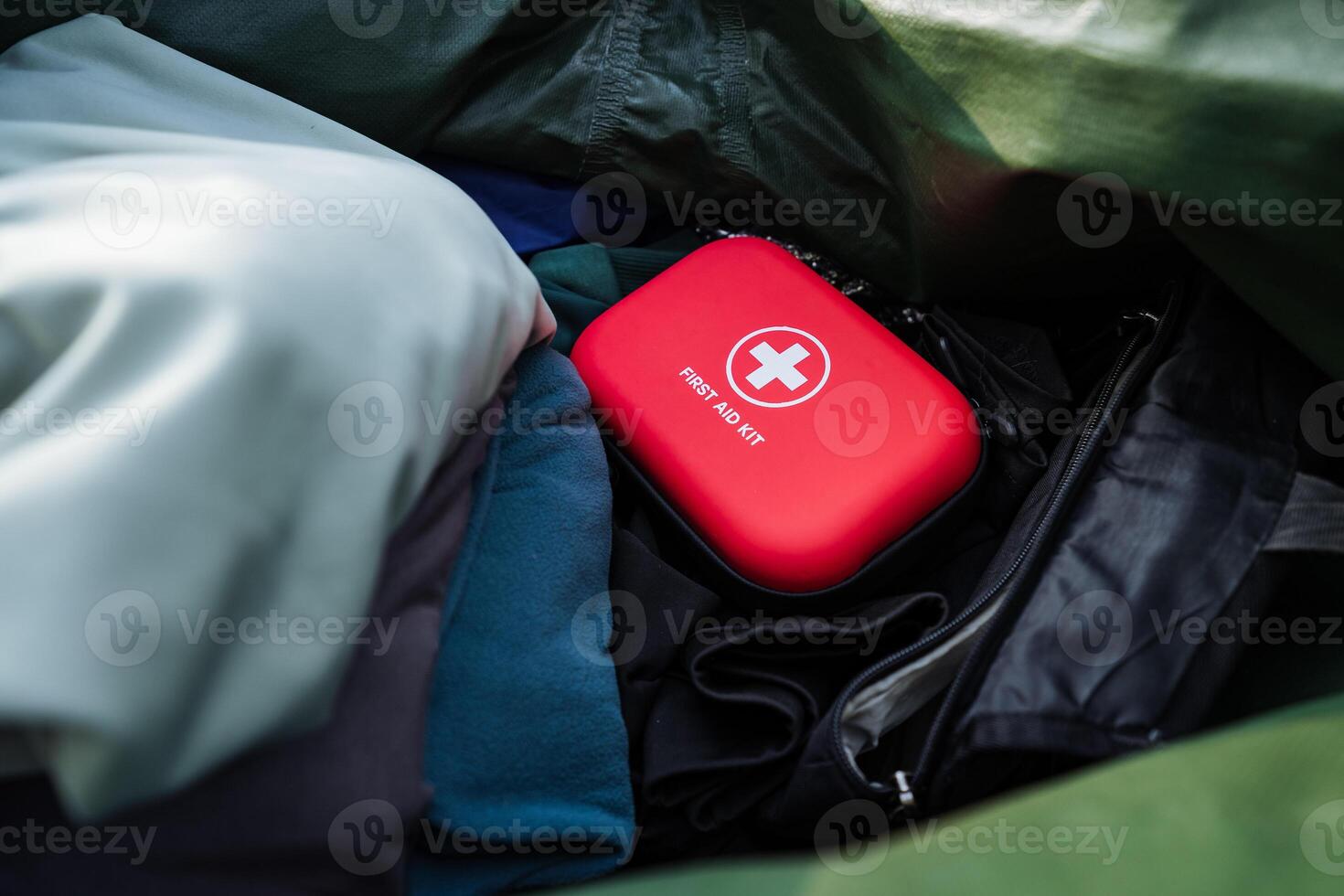 A Compact First Aid Kit is packed in a durable bag among clothing items, ensuring its easily accessible during emergencies while traveling or outdoor activities like hiking or camping photo