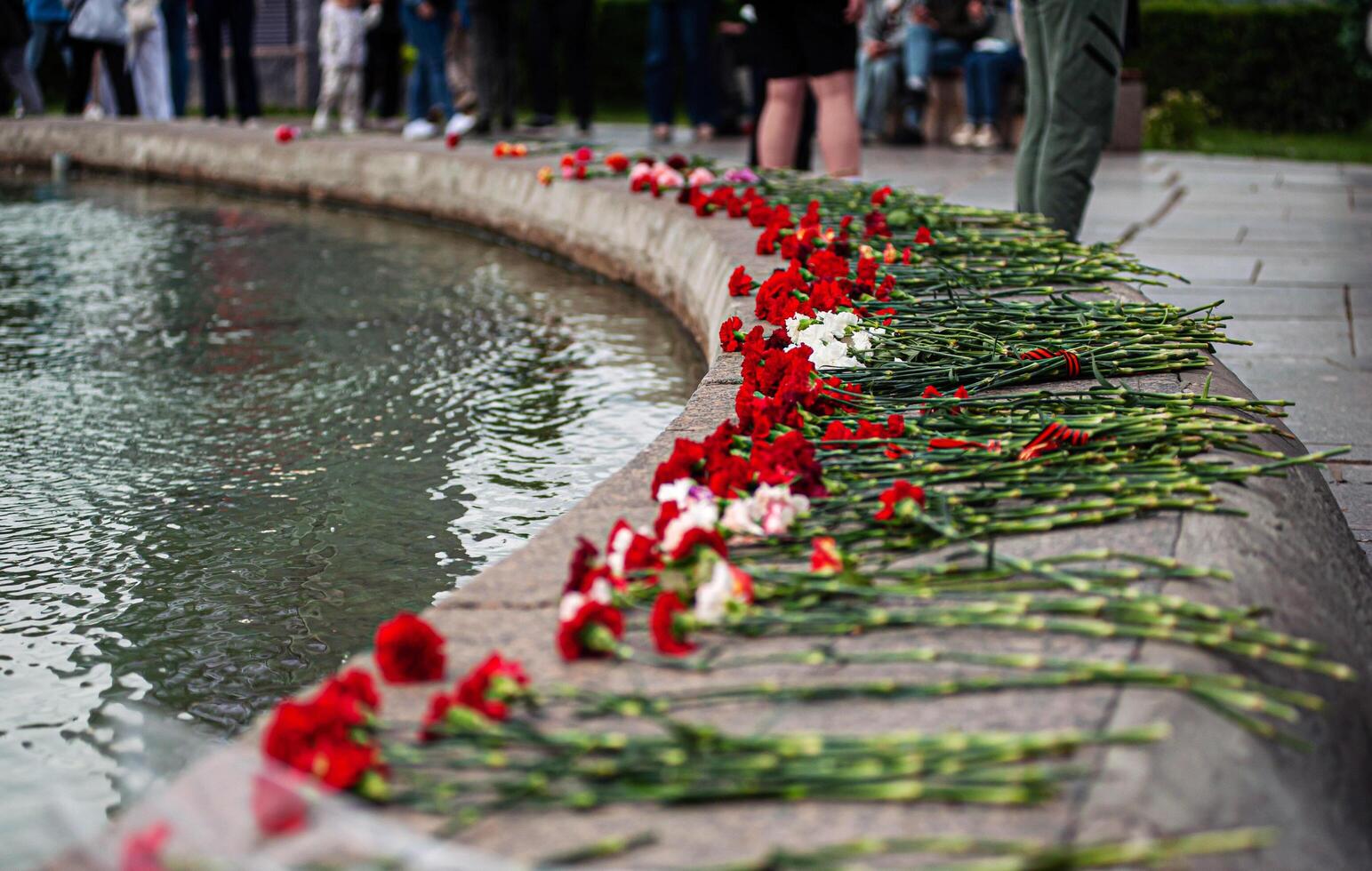 Memorial tribute with flowers laid near fountain in city park during commemorative event photo