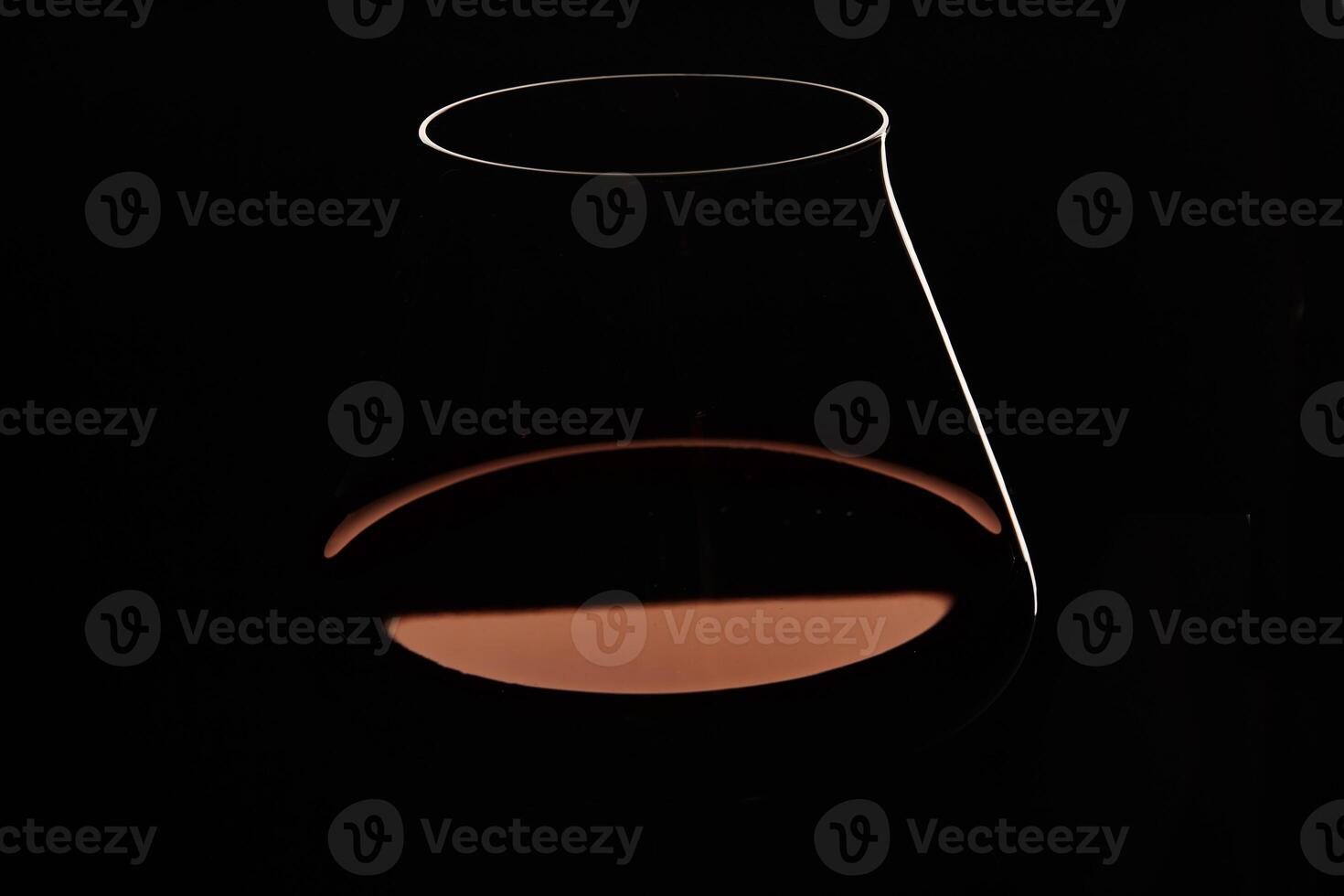 Silhouette of transparent glass with red wine on black. photo