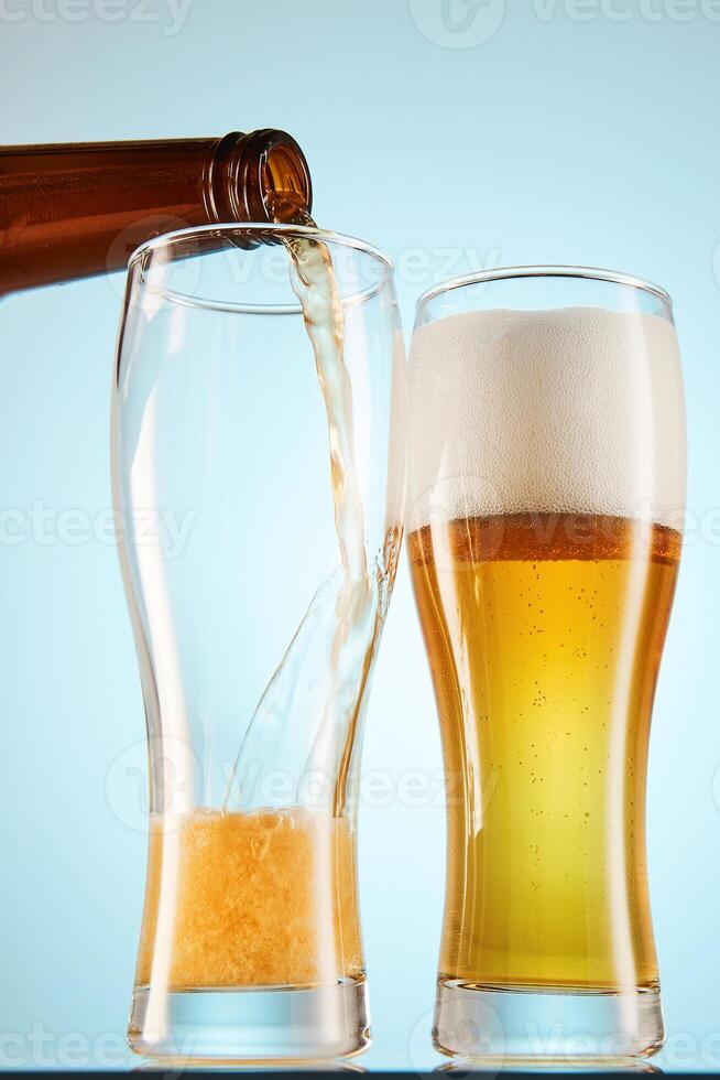 Lager, ale flows to empty tall glasses from bottle. photo