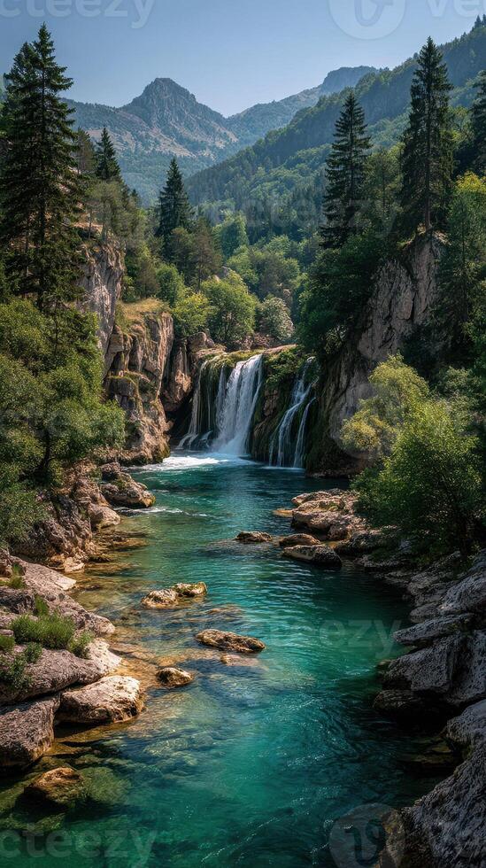 Serene waterfall cascading into turquoise pool surrounded by lush greenery in the mountains during midday photo