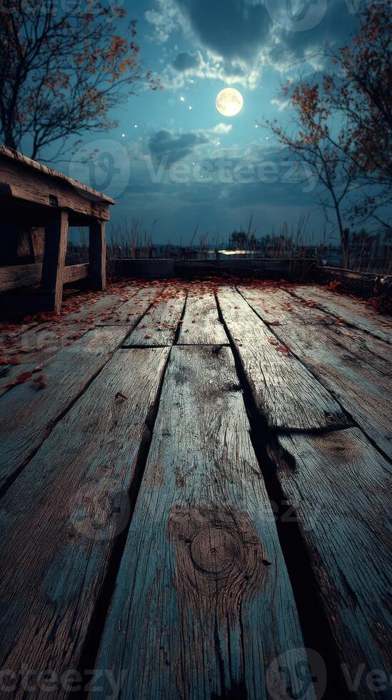 Nighttime view of a wooden dock under a bright moon with autumn leaves scattered on the floor and a calm lake in the background photo