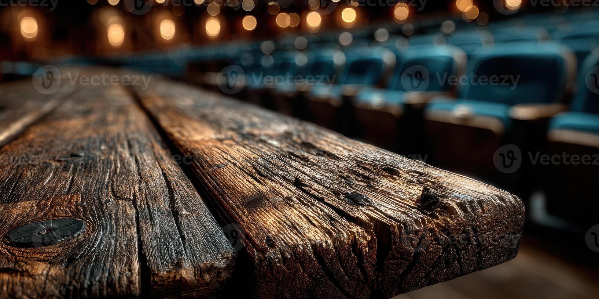 Wooden table in a theater with blue seats and warm ambient lighting in the background during a performance photo