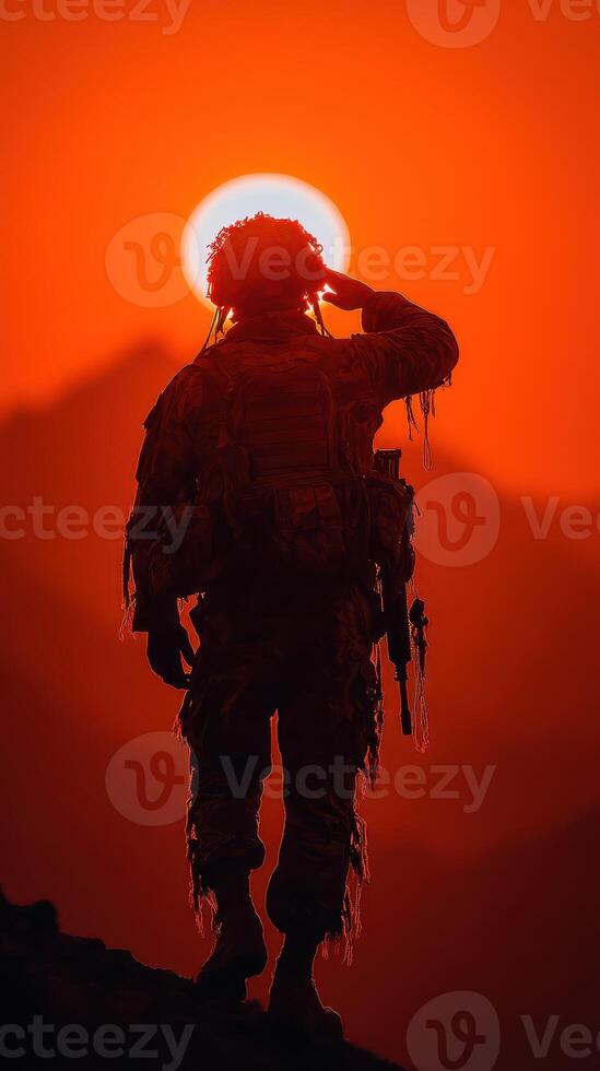 Soldier saluting against sunset backdrop in mountainous terrain during evening hours photo