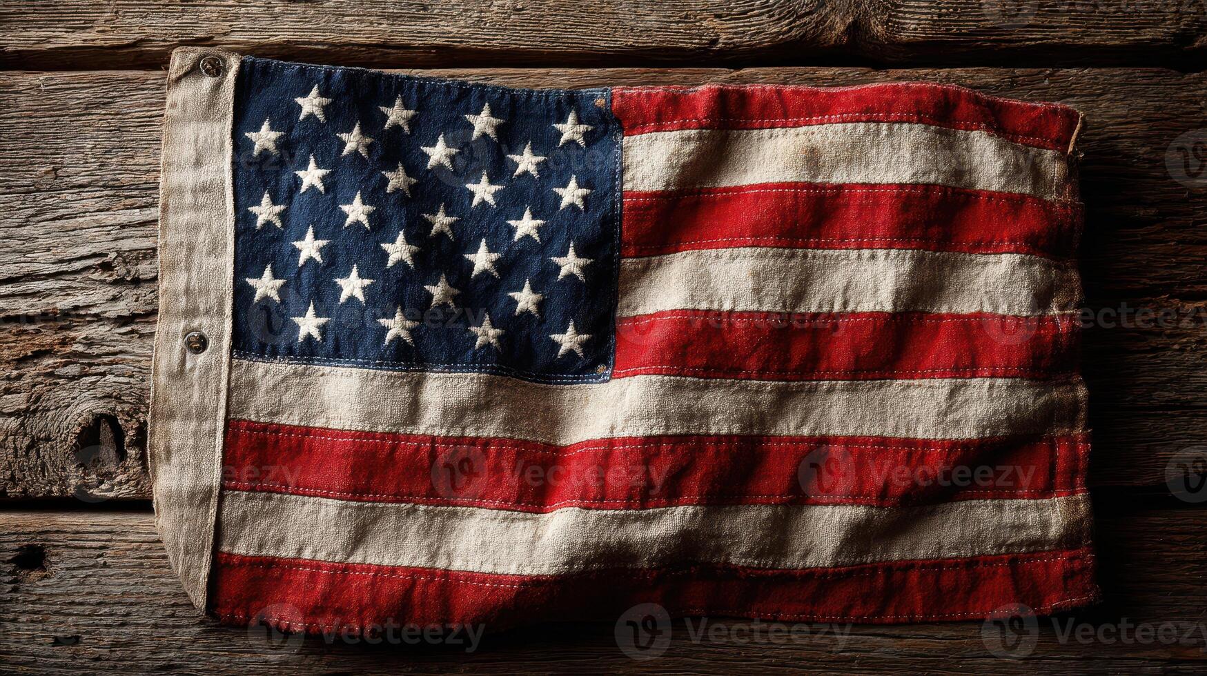 Vintage American flag displayed on a rustic wooden surface showcases its faded colors and historical significance photo