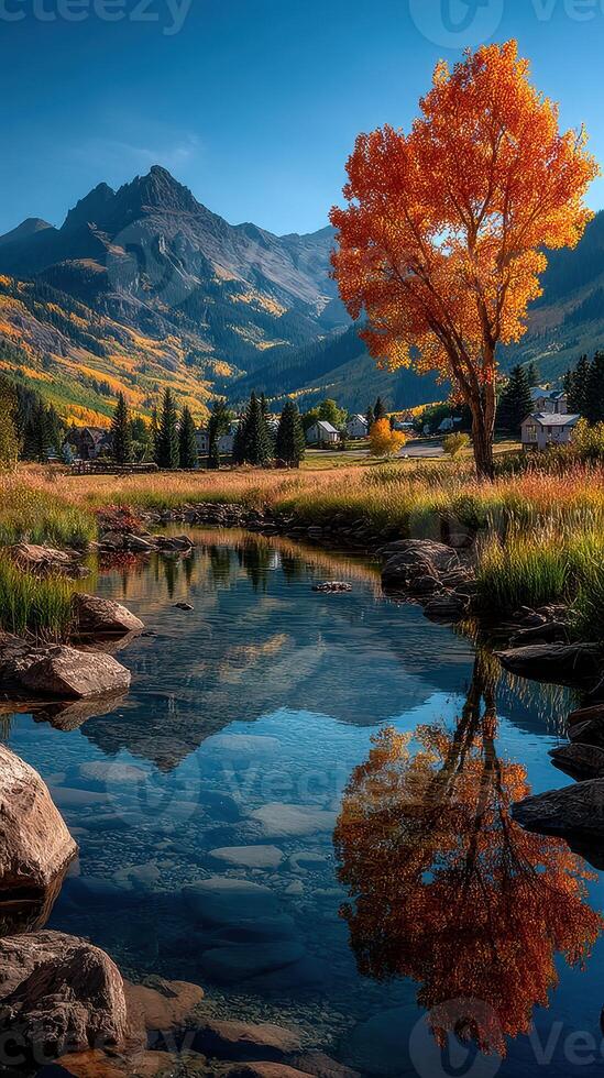 Vibrant autumn landscape with reflection of an orange tree in a serene mountain lake photo