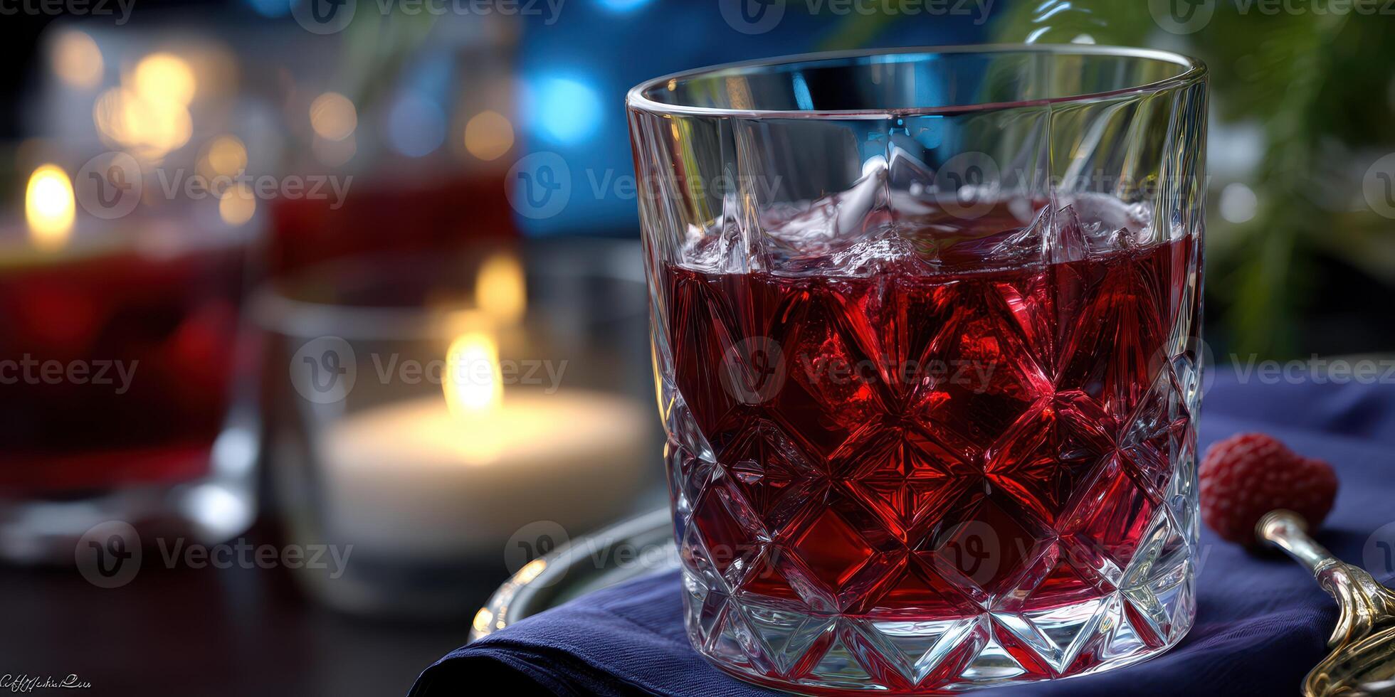 Colorful cocktail with ice served in a crystal glass on a tray surrounded by candles in an elegant setting photo
