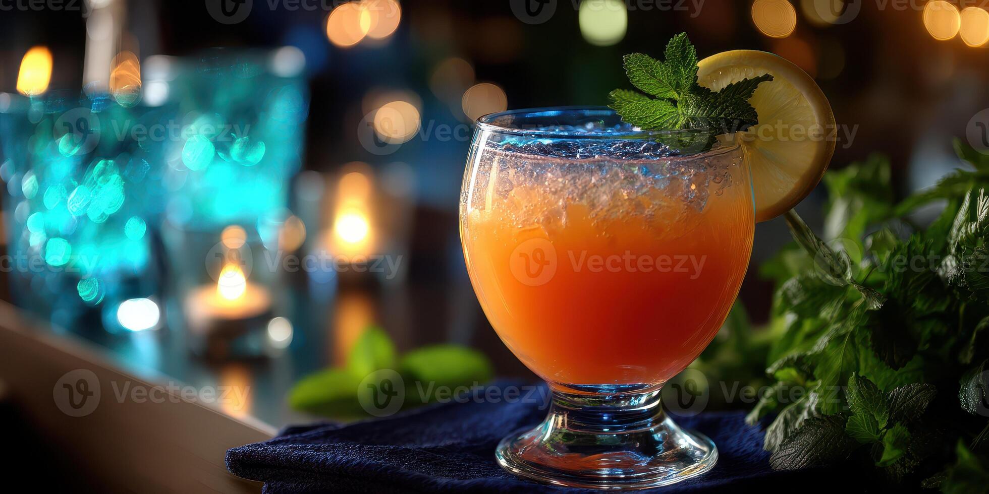 Colorful cocktail garnished with mint and lemon served in a glass on a bar countertop during an evening gathering photo