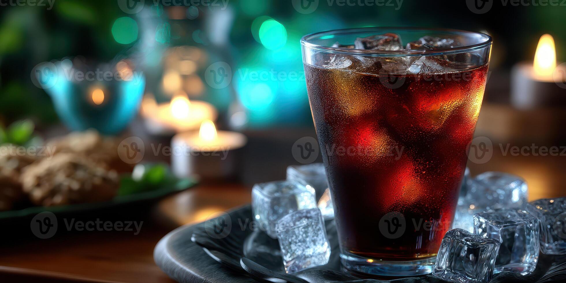 Refreshing dark beverage served with ice on a tray alongside cookies and candles in a cozy atmosphere photo
