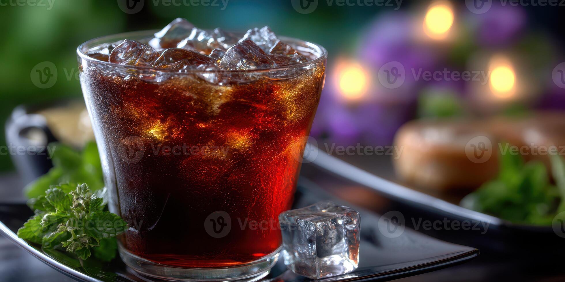 Refreshing cold beverage with ice in a glass served on a black plate surrounded by greenery and soft lighting photo