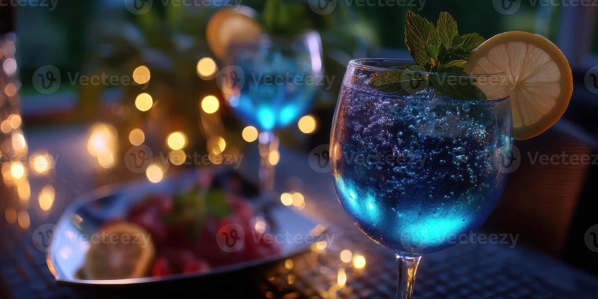 Blue sparkling drink garnished with mint and lemon on a dimly lit table with berries during an evening gathering photo