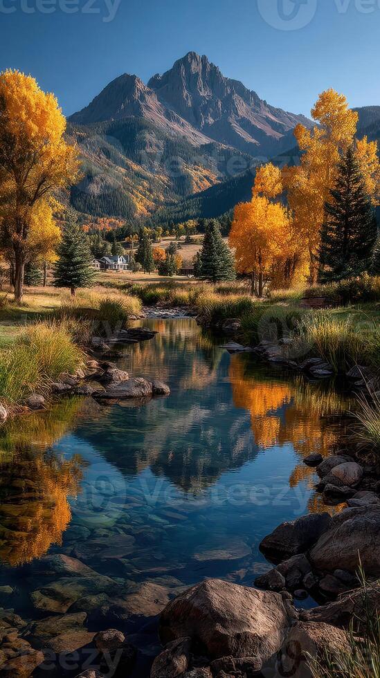 Beautiful autumn landscape with colorful trees and mountain reflections in peaceful stream photo