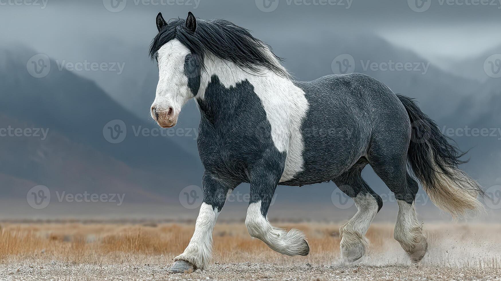 Majestic horse gallops through a scenic landscape with mountains in the background during a cloudy day photo