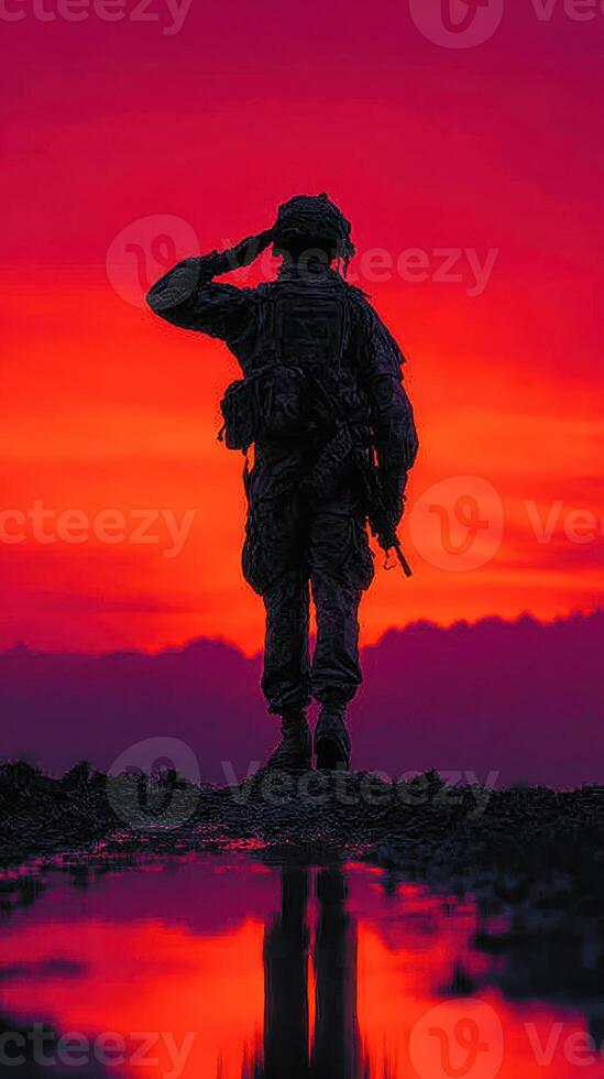 Soldier saluting against a vibrant sunset in a mountainous landscape during early evening hours photo