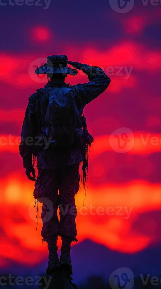 Soldier saluting at sunset with vibrant colors illuminating the sky in the background photo