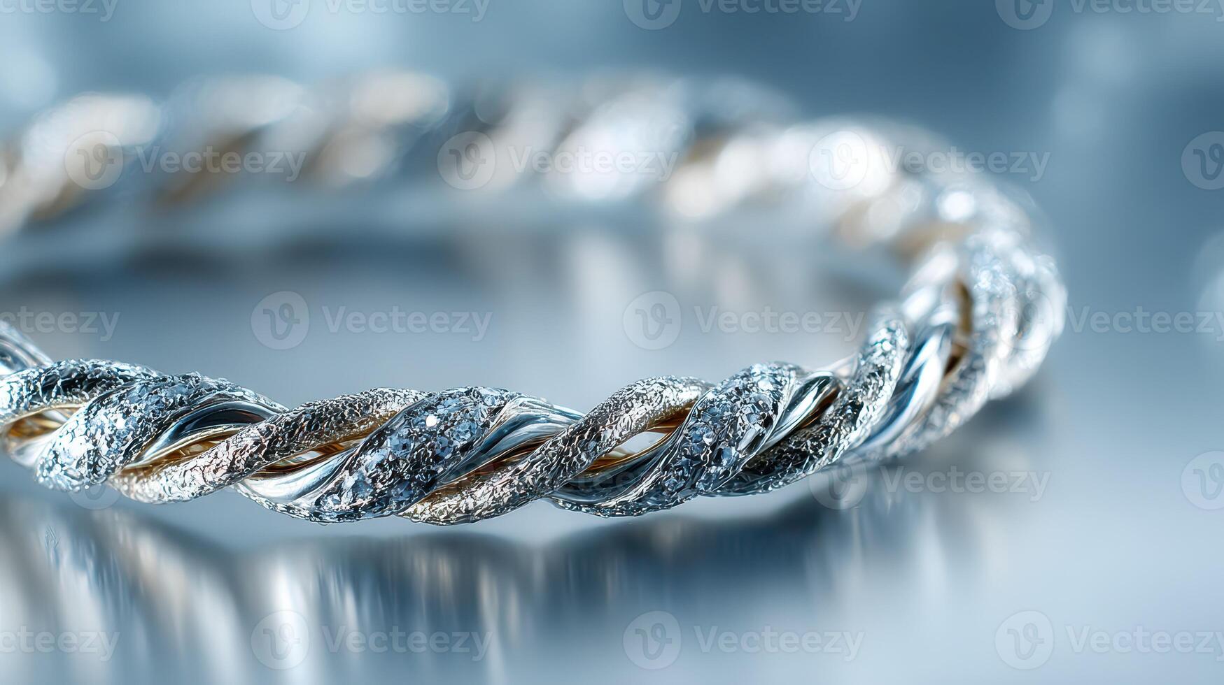 Elegant silver and gold twisted bracelet shines under soft light in a close-up view on a reflective surface photo