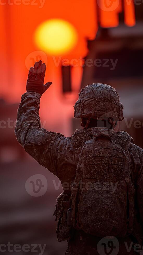 Soldier waves goodbye against a striking sunset in a military area photo