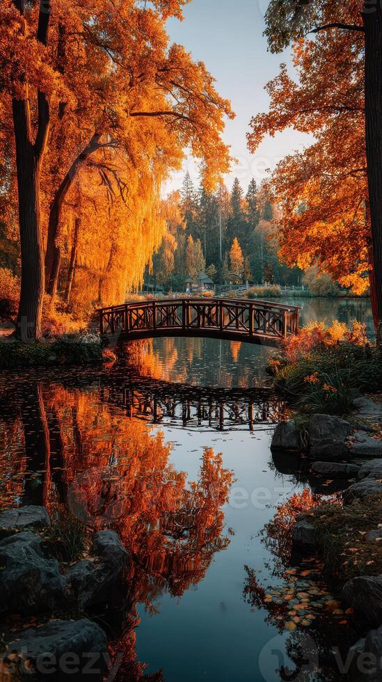 Enchanting autumn landscape with a wooden bridge reflecting in still waters at a serene park during sunset photo