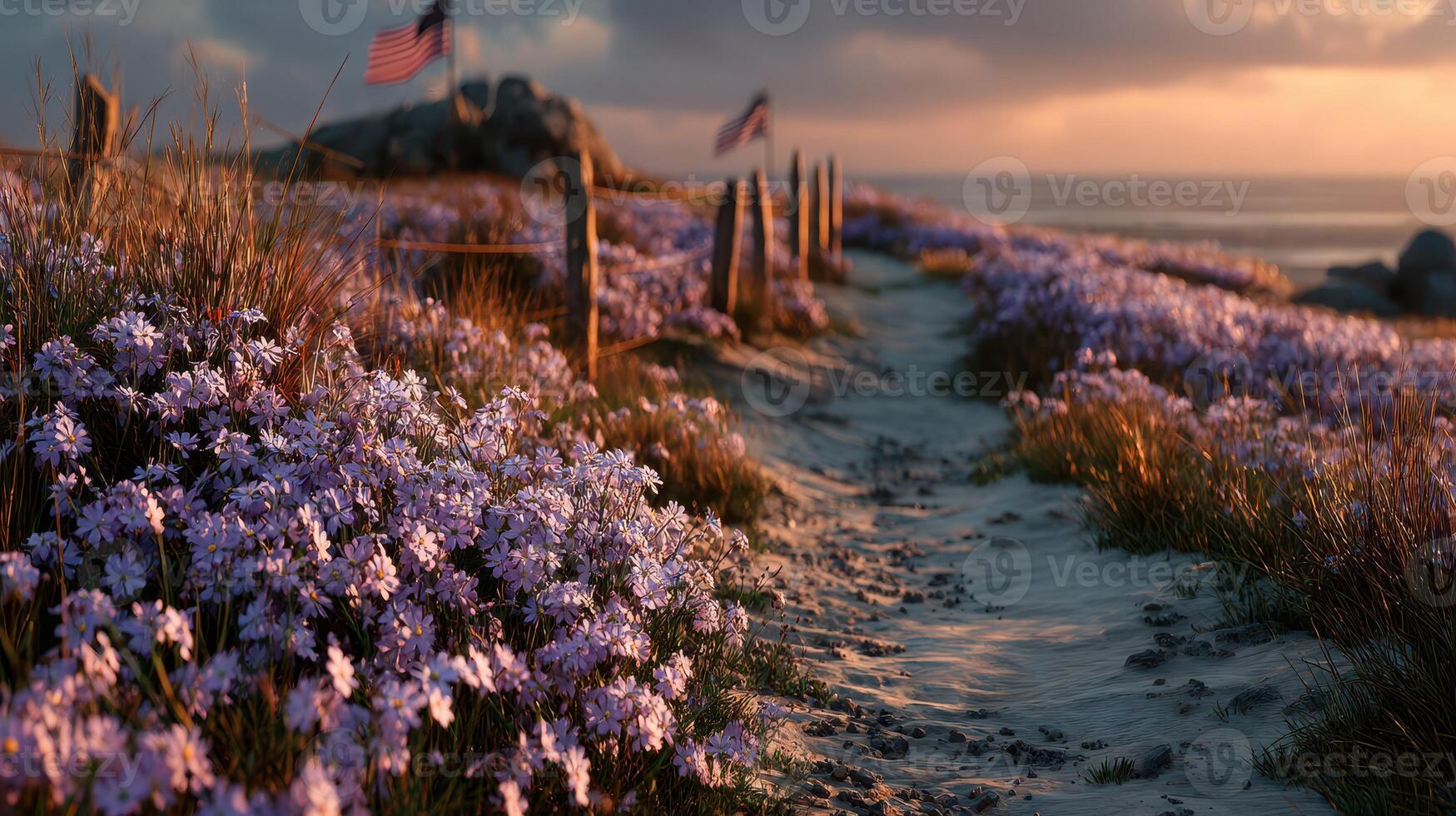 Beautiful sunset over a coastal path lined with flowers and flags near the shore photo