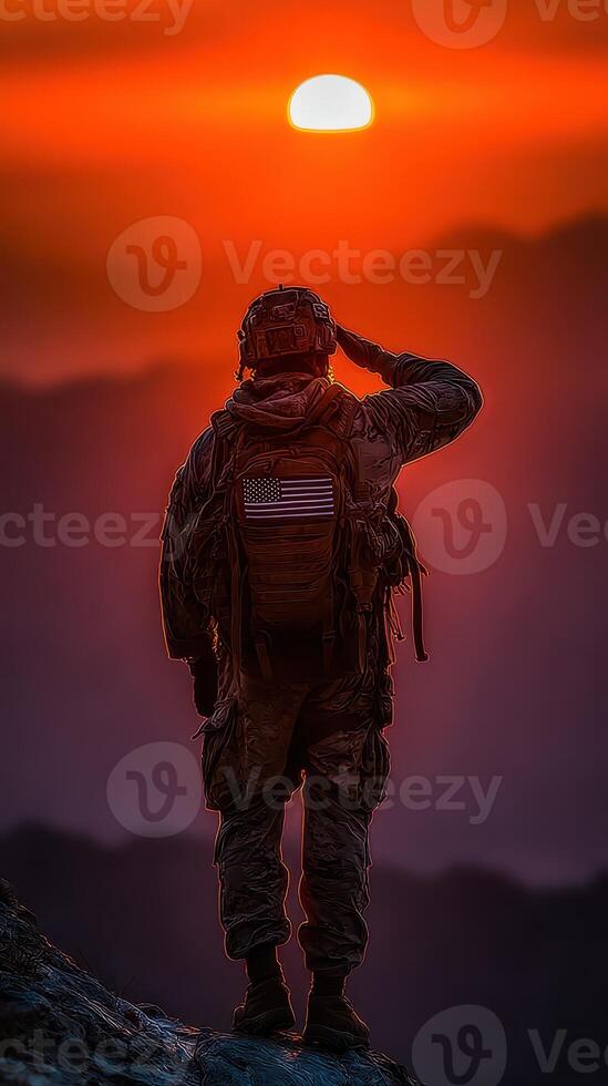 Soldier saluting the sunset while standing on a rocky peak in a mountainous region photo