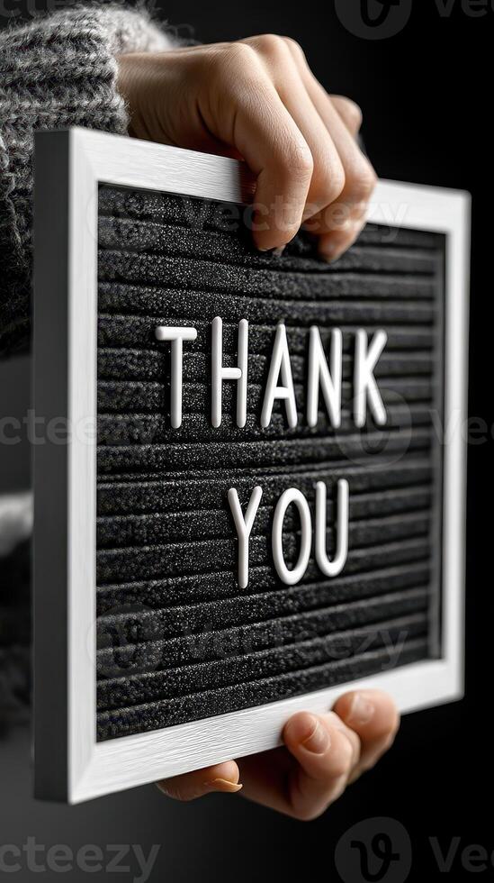 Hand holding a thank you sign with a black background highlighting gratitude and appreciation photo