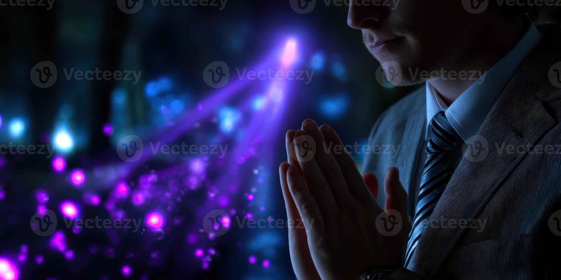 Person in suit with hands clasped, surrounded by glowing purple and blue lights at a mysterious location during an evening event photo