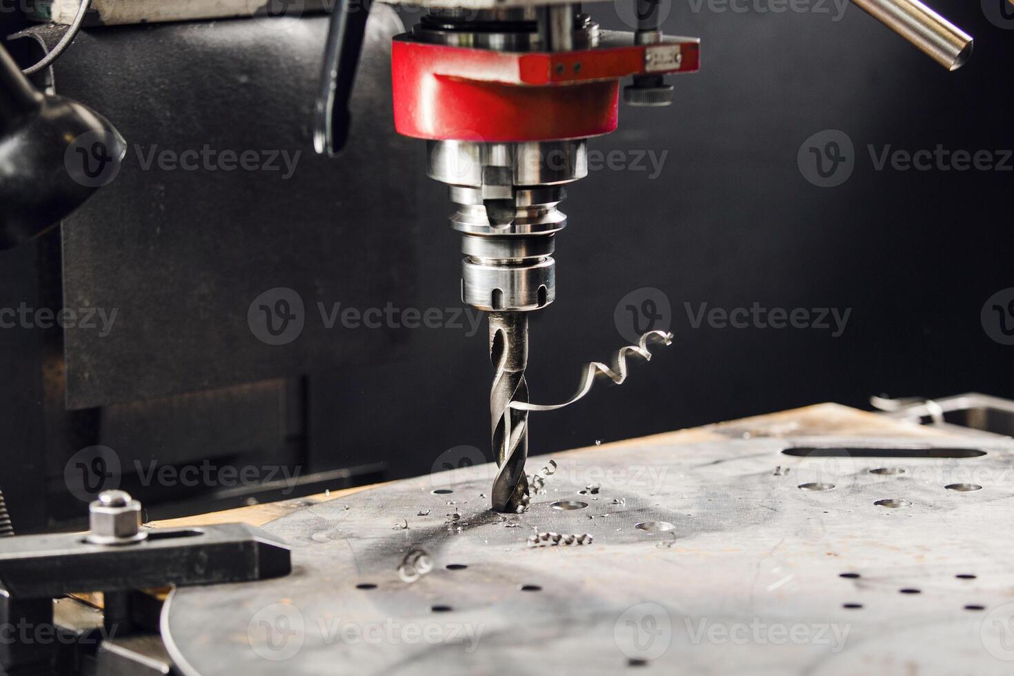 Drilling the under bolt hole. Vertical drill makes holes in metal part. photo