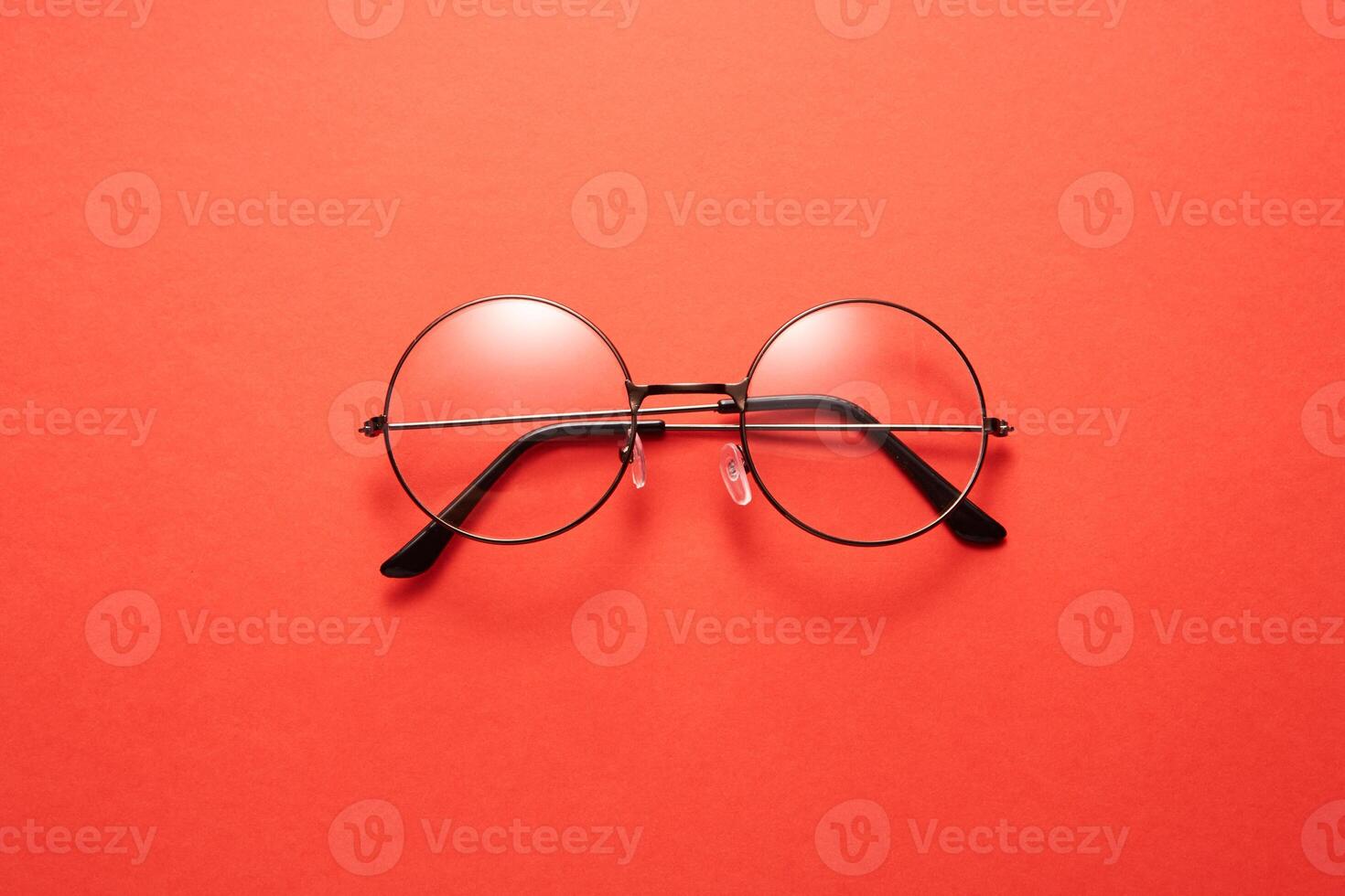 Glasses in round thin metal frame isolated on red surface. photo