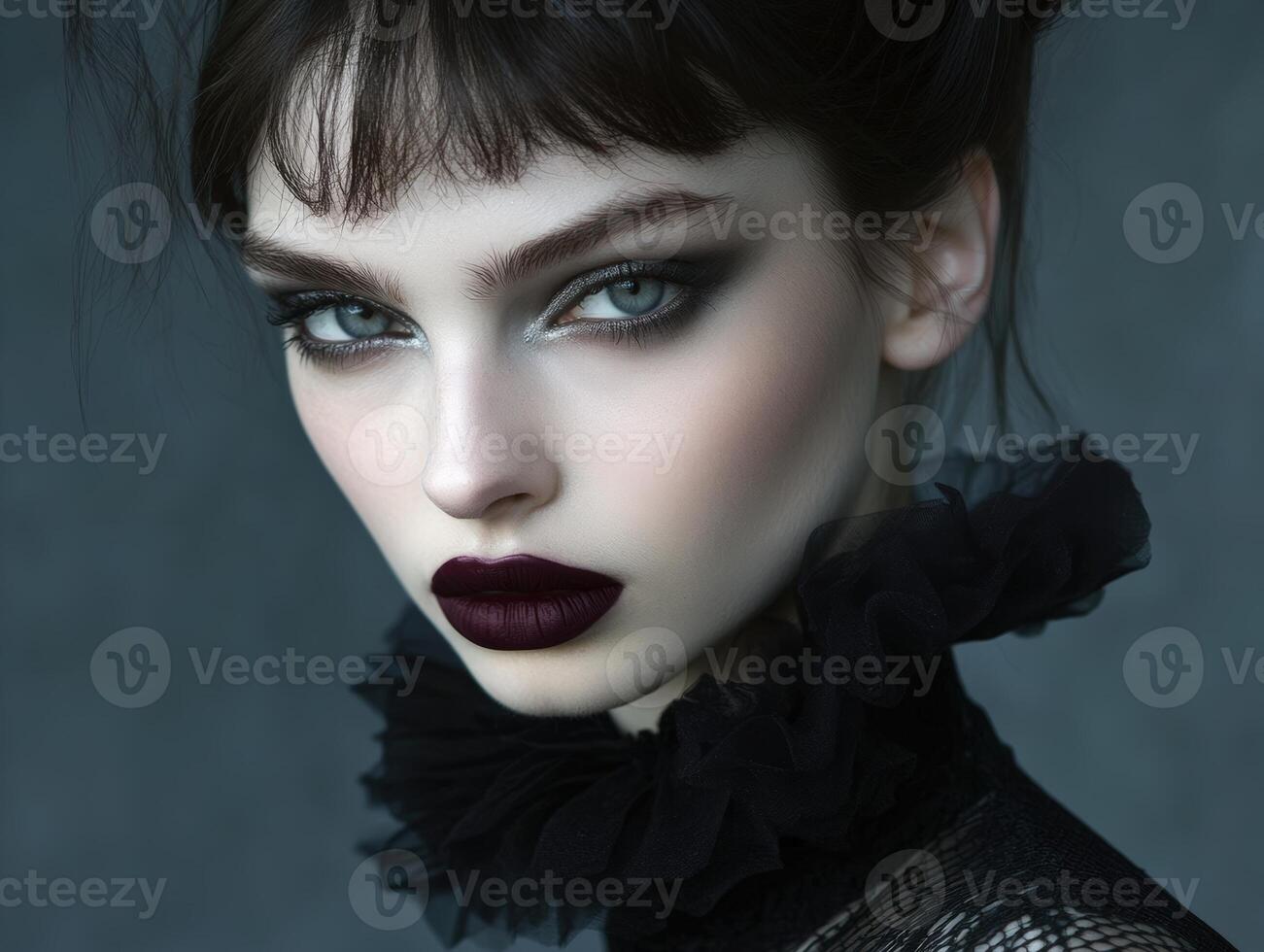 Striking portrait of a woman with bold makeup, dark lipstick, and captivating eyes, wearing a ruffled black collar against a soft focus backdrop. Her gaze is intense and mysterious photo