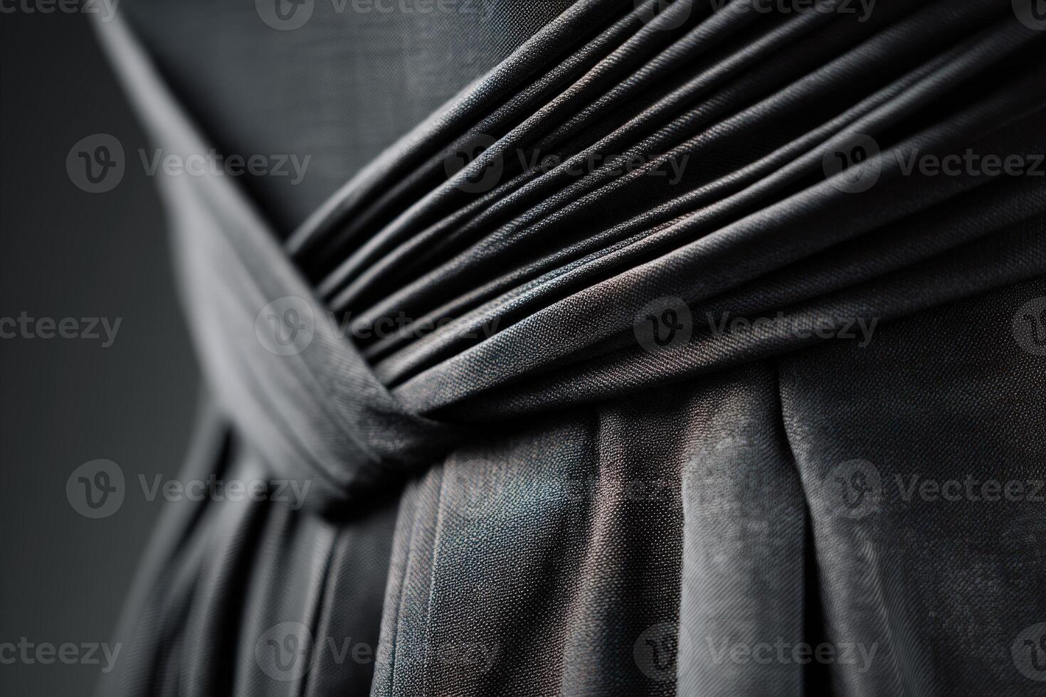 Dark elegant fabric with intricate pleats and folds, creating a textured and flowing appearance. Light subtly highlights the contours, adding depth and contrast to the material photo