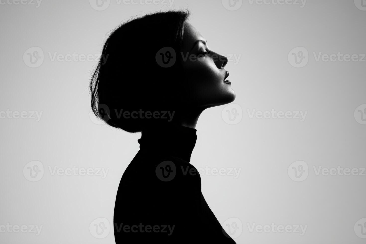 A monochromatic side profile portrait of a woman with short hair, wearing a turtleneck. Her face is gracefully lit, highlighting her features against a soft gradient background photo