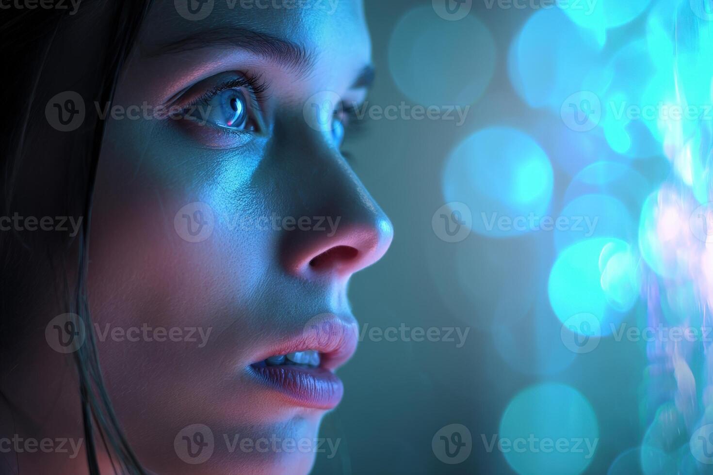A woman's face is illuminated by soft blue and pink light, gazing intently at glowing orbs. Her expression is thoughtful with a serene background of blurred bokeh circles photo