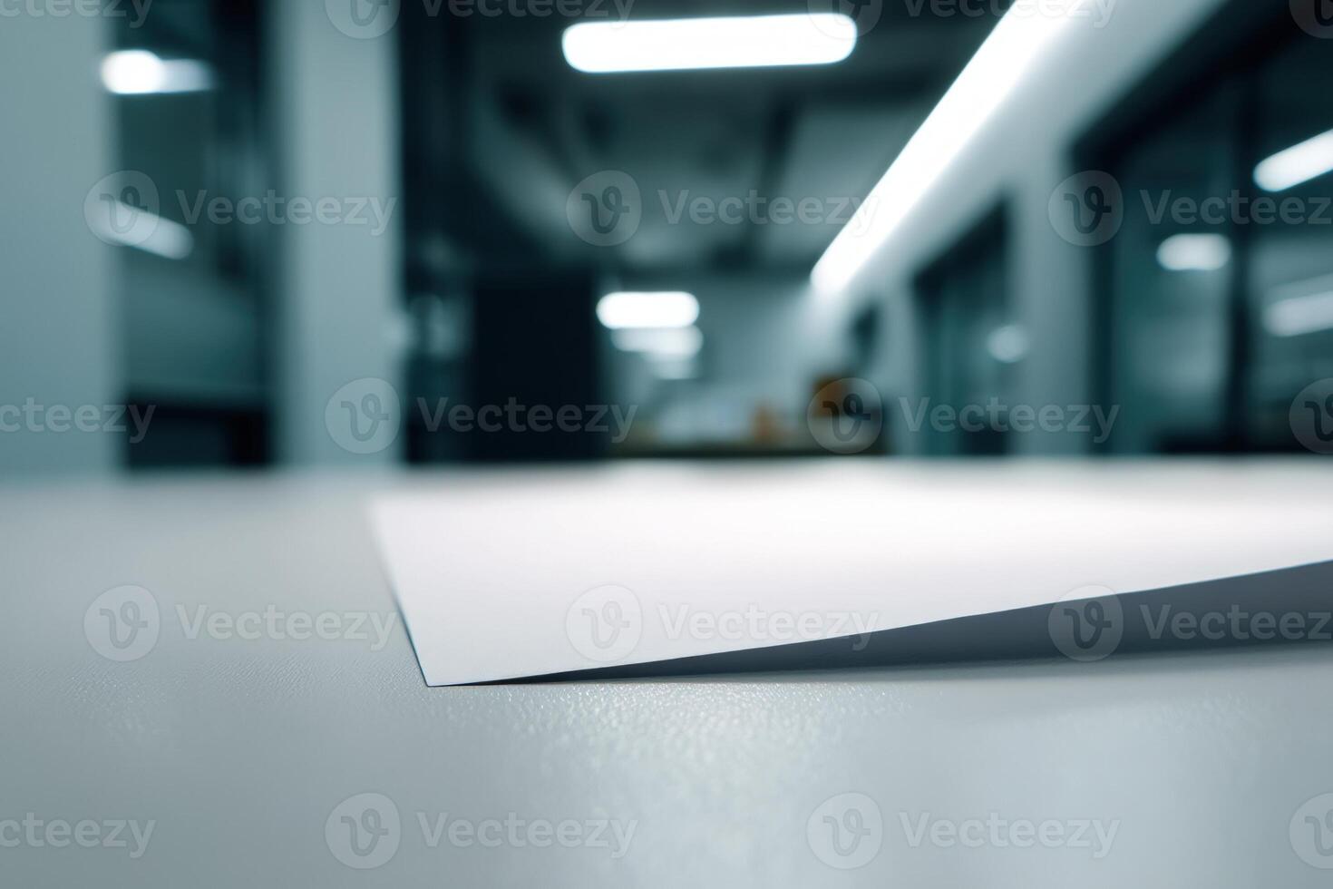 Paper rests on a smooth surface in a modern, dimly lit office space. Fluorescent lights illuminate the room's ceiling, creating reflections on the glossy table photo